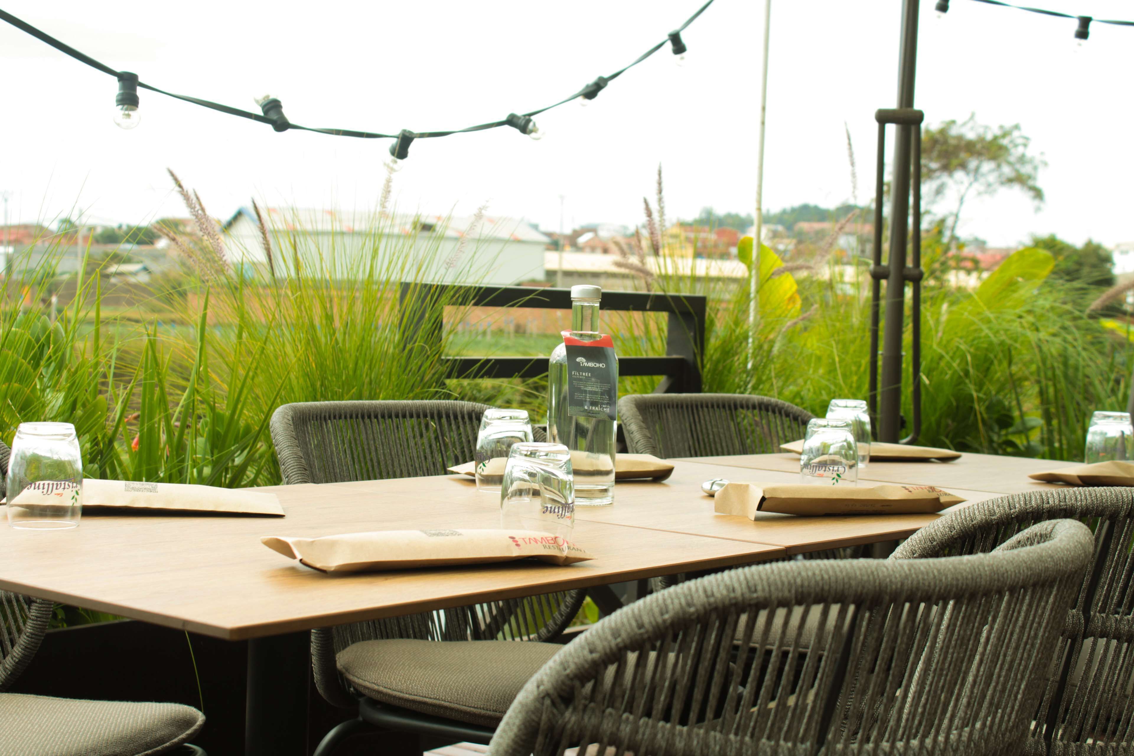 An outdoor dining area with wicker chairs, a wooden table, and string lights.