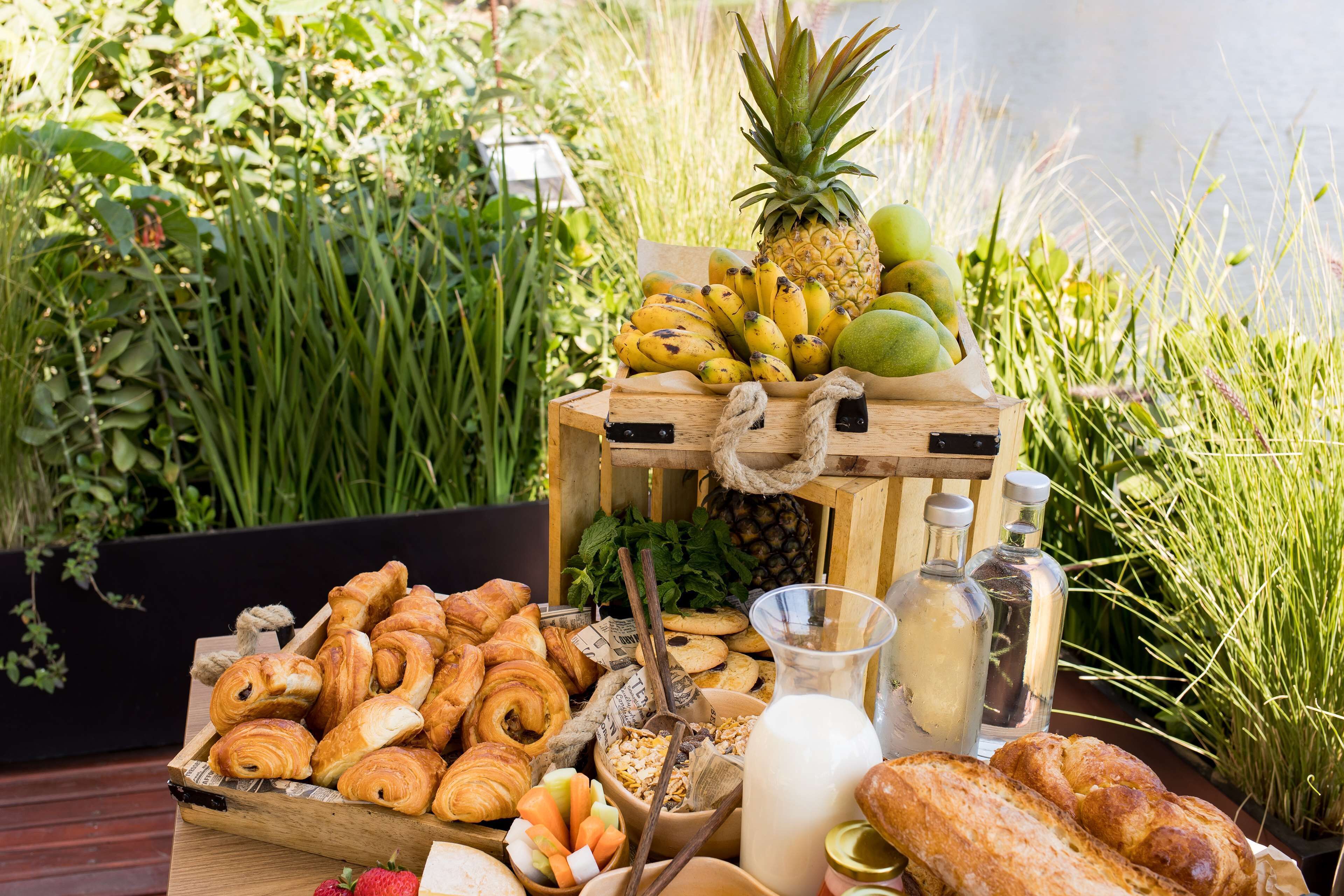 Una mesa de madera con una variedad de alimentos, como pasteles, frutas y botellas.