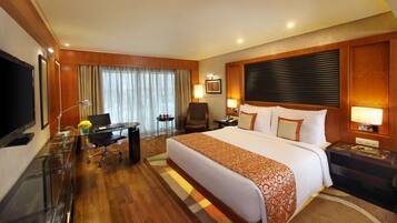 Une chambre d’hôtel avec un grand lit, un bureau avec une chaise, une télévision et une lampe.