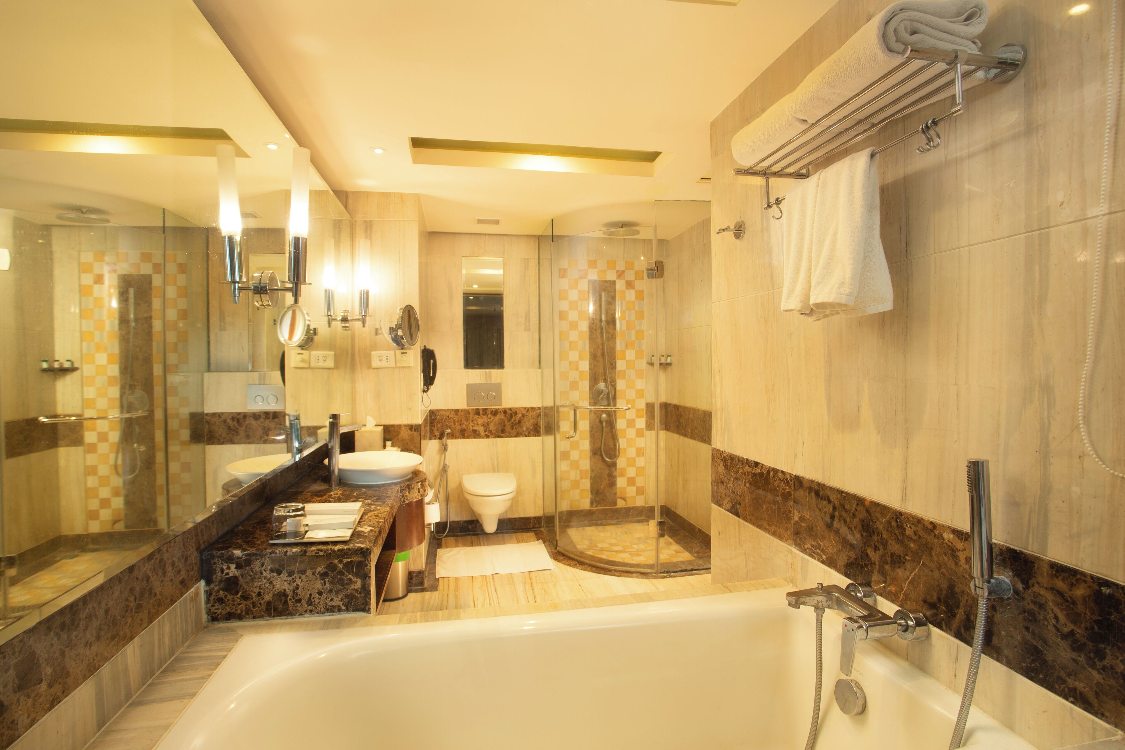 A modern bathroom with a bathtub, a glass-enclosed shower, a sink, and a toilet.