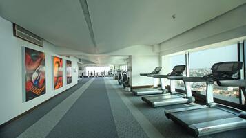 A gym with treadmills, exercise bikes, and a long corridor with artwork on the walls.