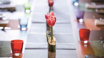 A table with a vase containing a single red tulip, surrounded by red glasses.