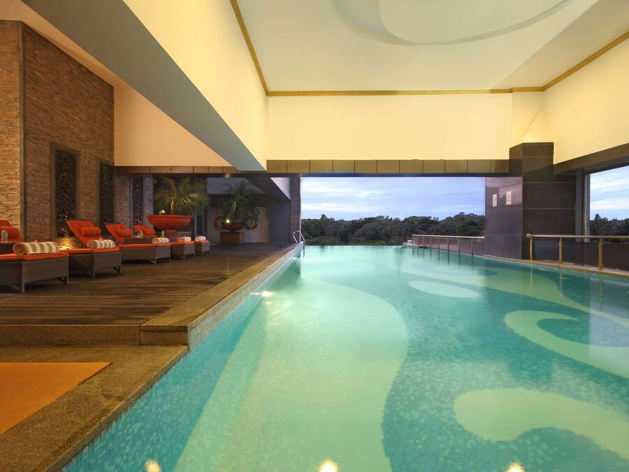 Una piscina con sillas de descanso y vista al cielo.
