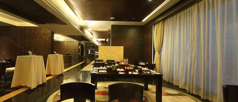 A modern dining area with tables set for a meal, a long corridor, and a large window with curtains.