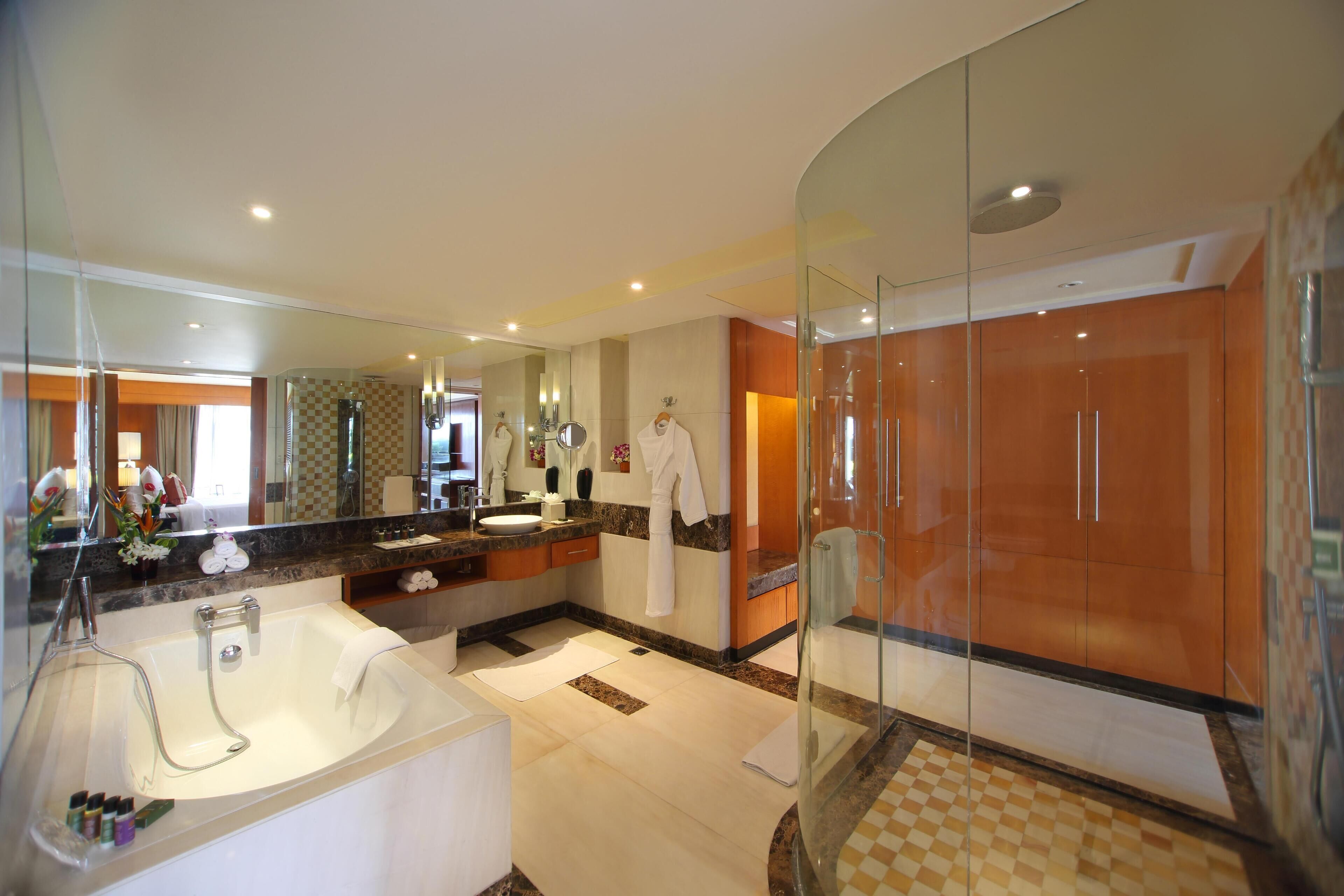 A modern bathroom with a large bathtub, a glass-enclosed shower, and a vanity with a mirror.