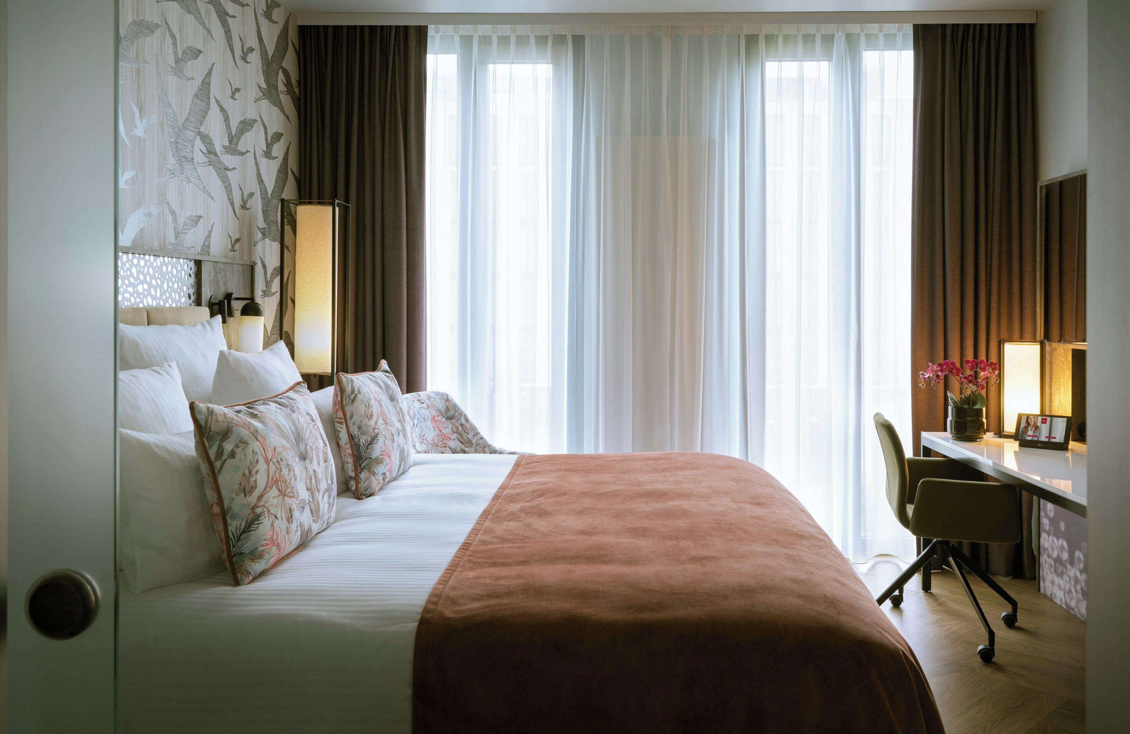 A hotel room with a large bed, a desk, and a chair.