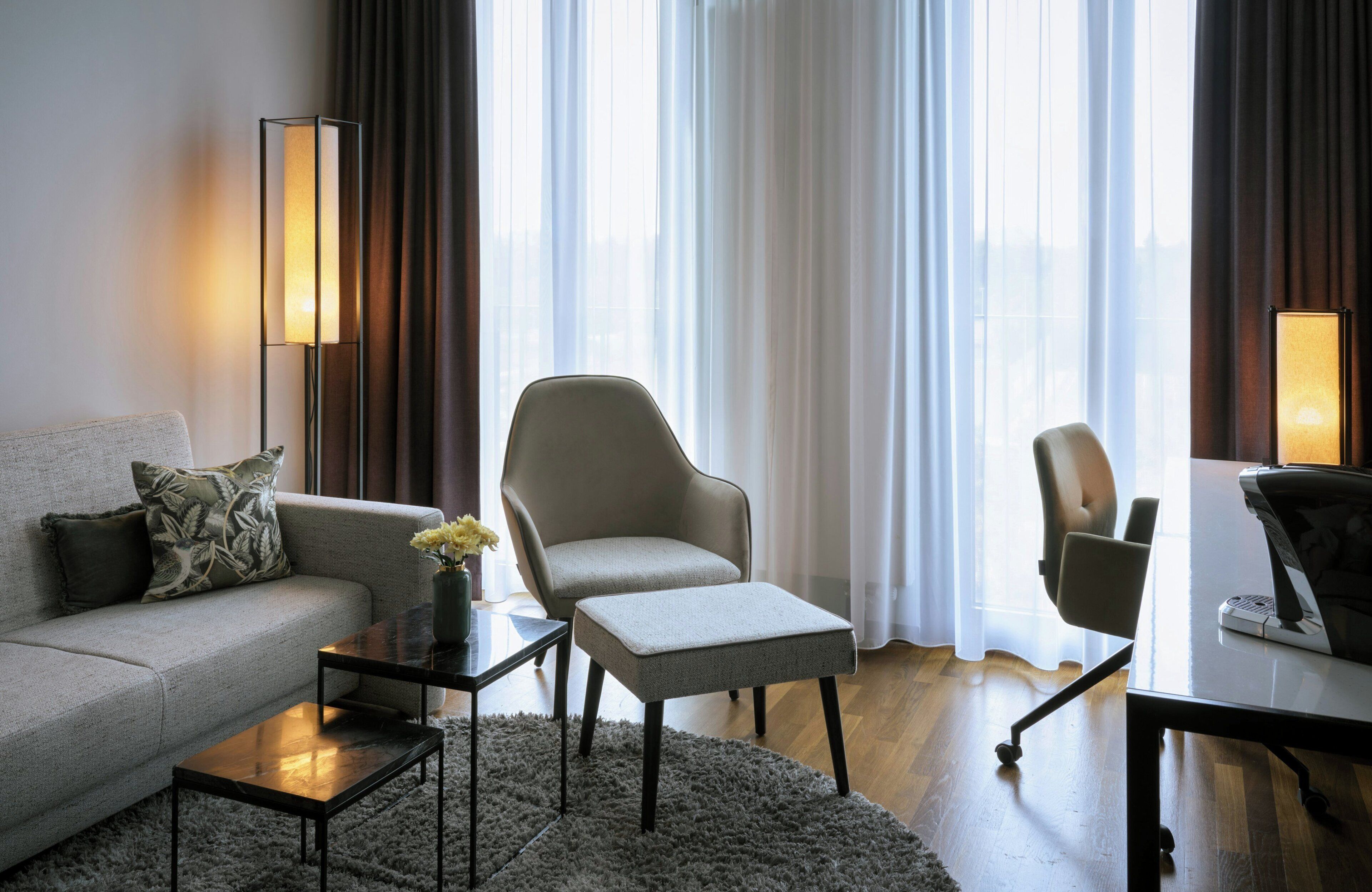 Un salon moderne comprenant un canapé, un fauteuil, une table basse et une petite table d’appoint.
