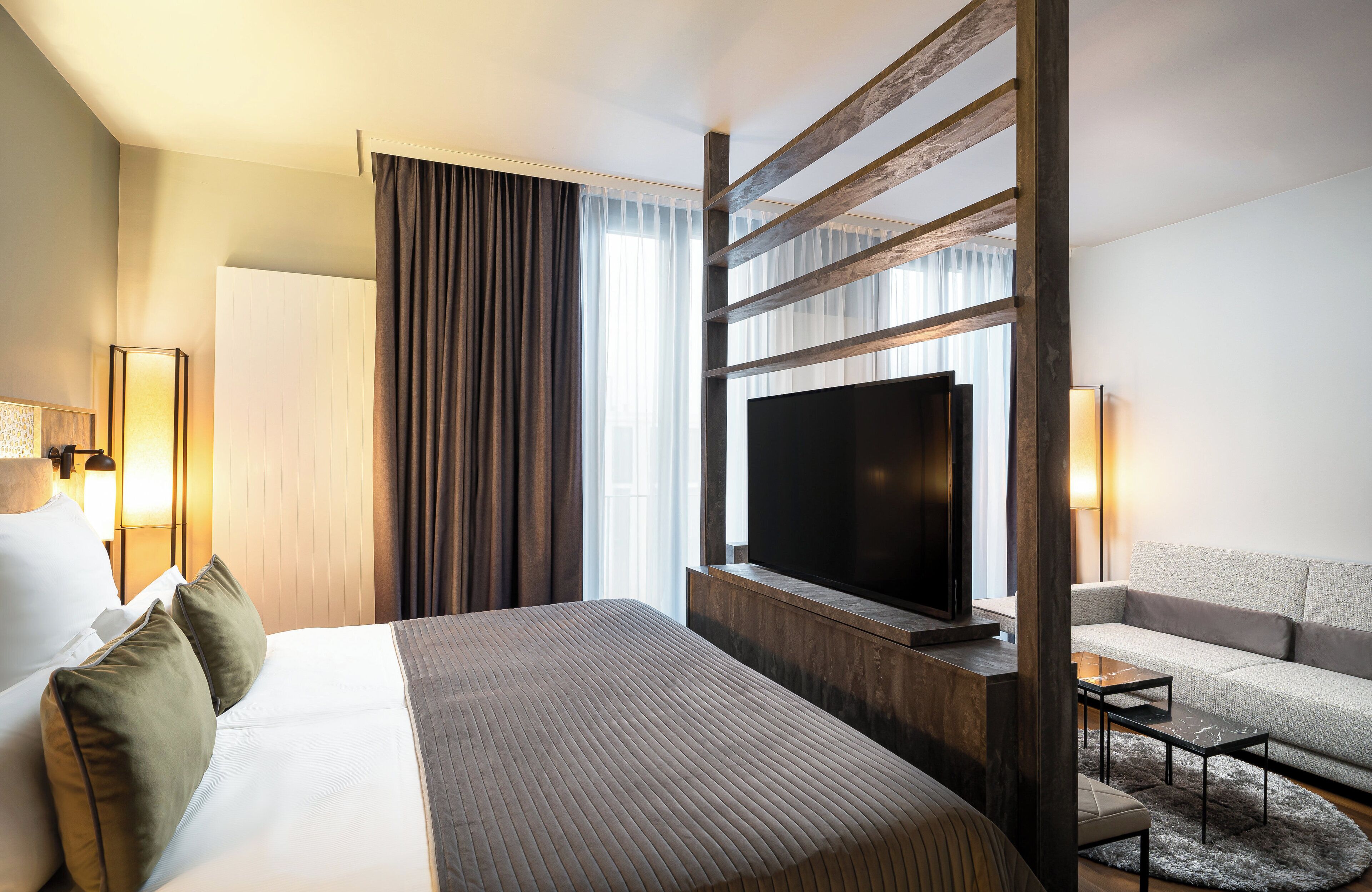 A hotel room with a large bed, a flat-screen TV, a sofa, and a desk.