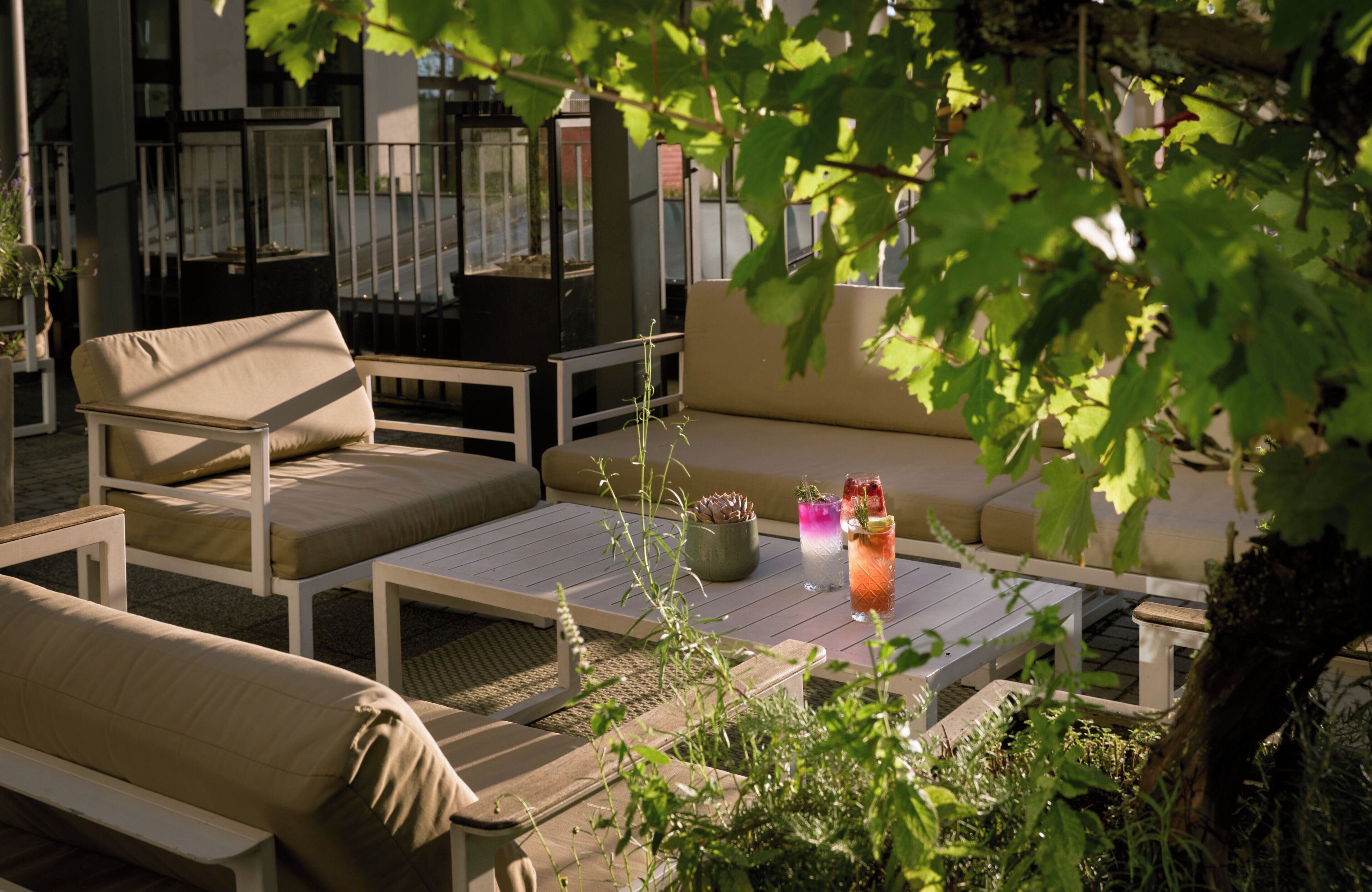 Un área de estar al aire libre con un sofá, sillas y una mesa. Hay bebidas sobre la mesa.