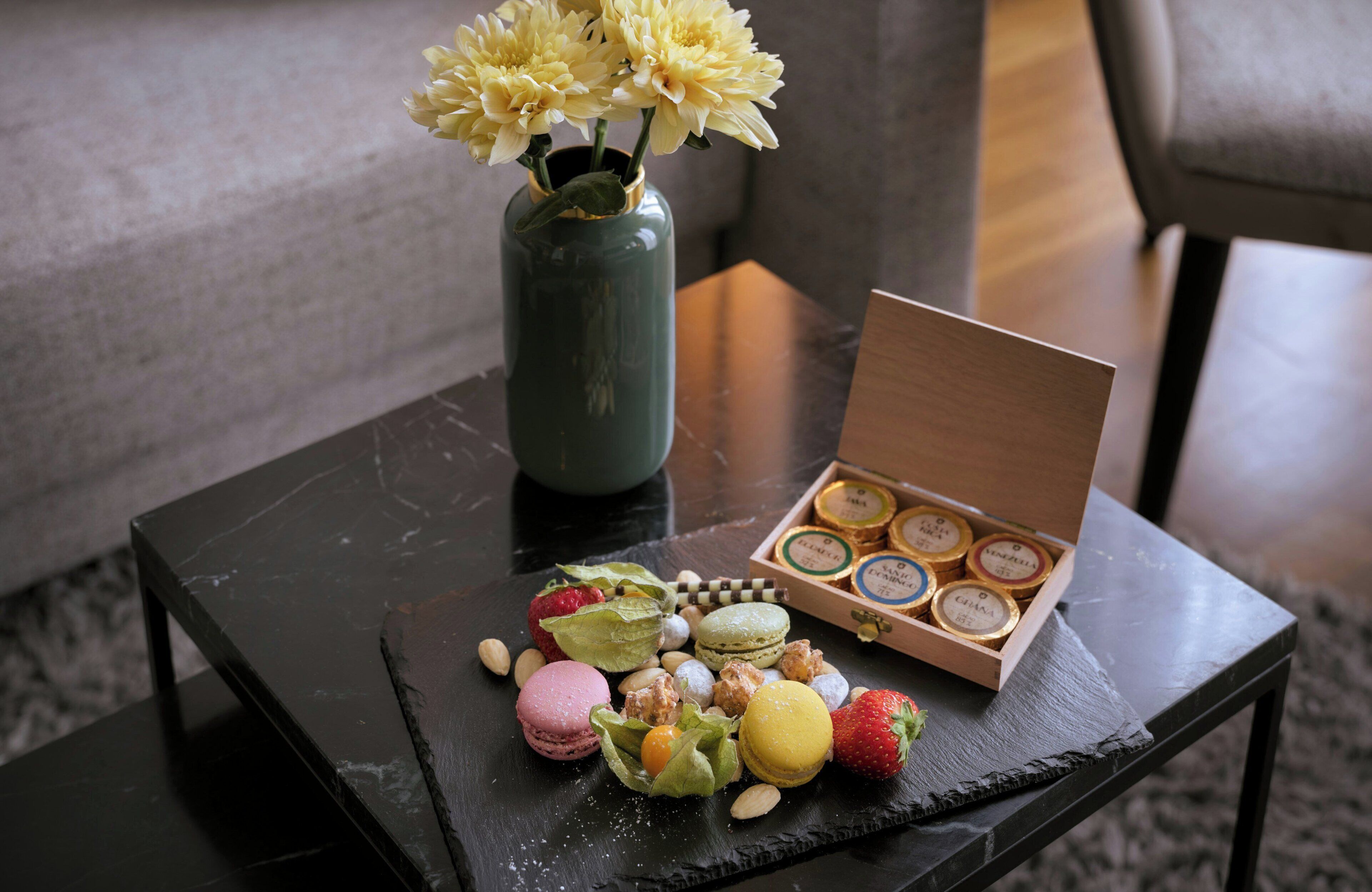 Ein Tisch mit einer Blumenvase, Pralinen und Macarons.
