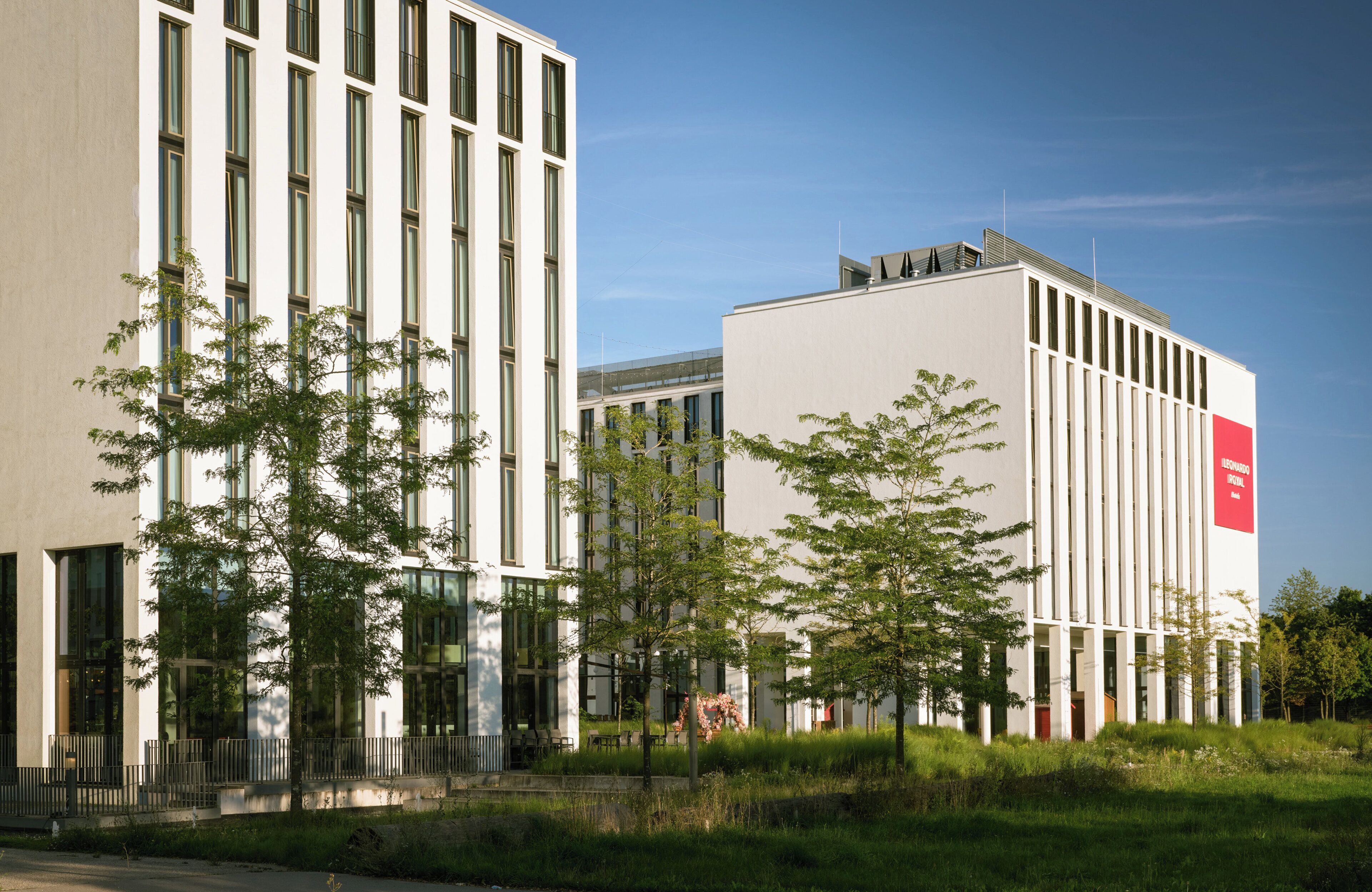 Ein modernes Gebäude mit großen Fenstern und einem roten Schild an der Seite.