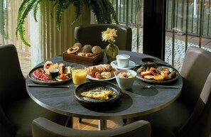 A breakfast table with various dishes, a coffee cup, and a vase with flowers. - Leonardo Royal Hotel Munich (Munich)