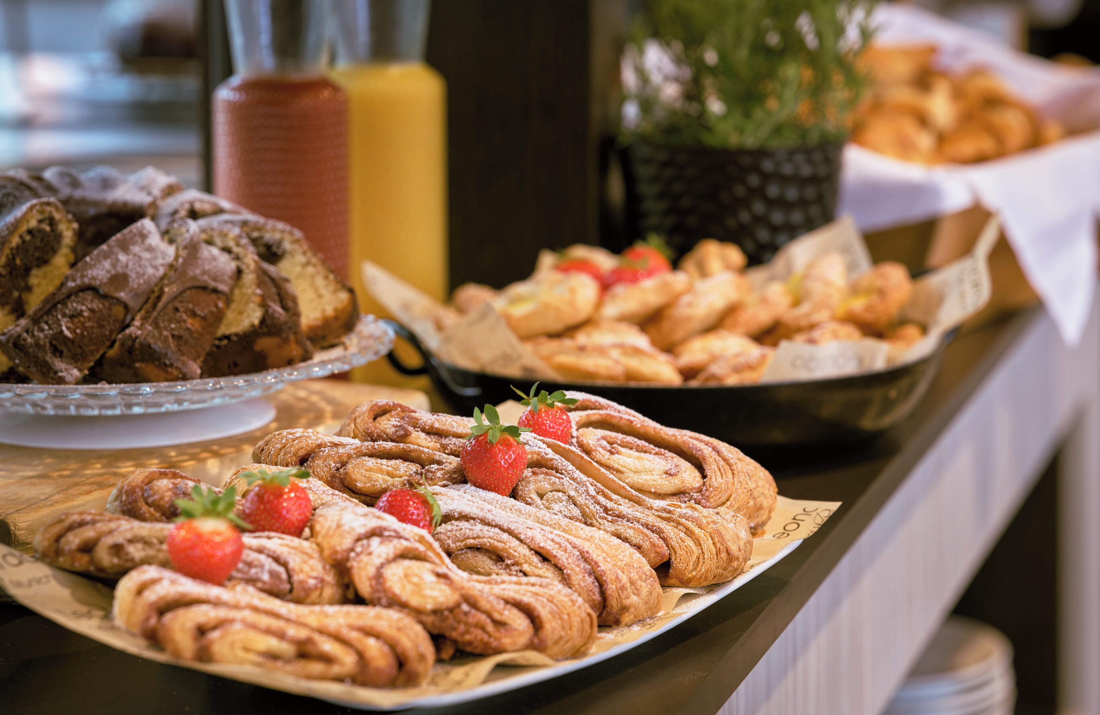 Une table de buffet proposant une variété de pâtisseries, notamment des brioches à la cannelle et d’autres produits de boulangerie.