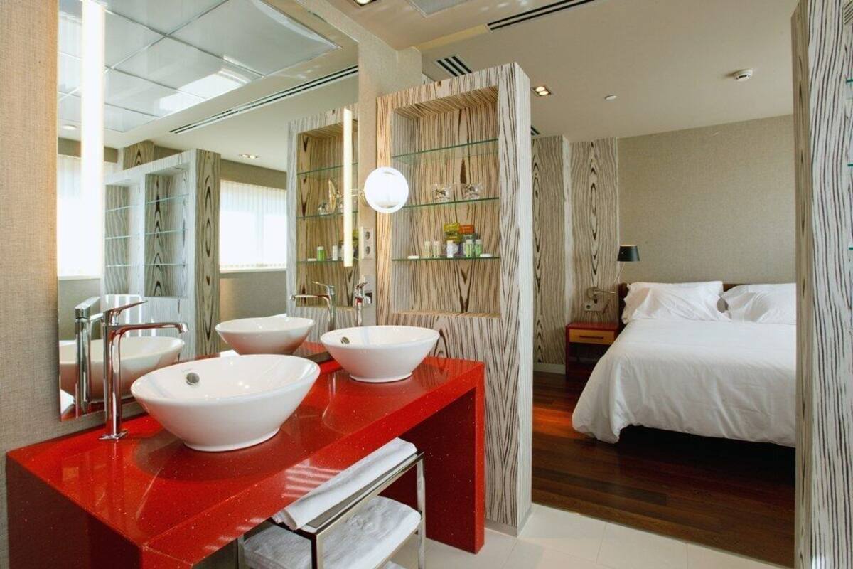 A modern bathroom with a red vanity, two white sinks, a large mirror, and a wooden wall panel.