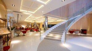 Un vestíbulo amplio con una escalera curva, muebles modernos y un área de descanso.