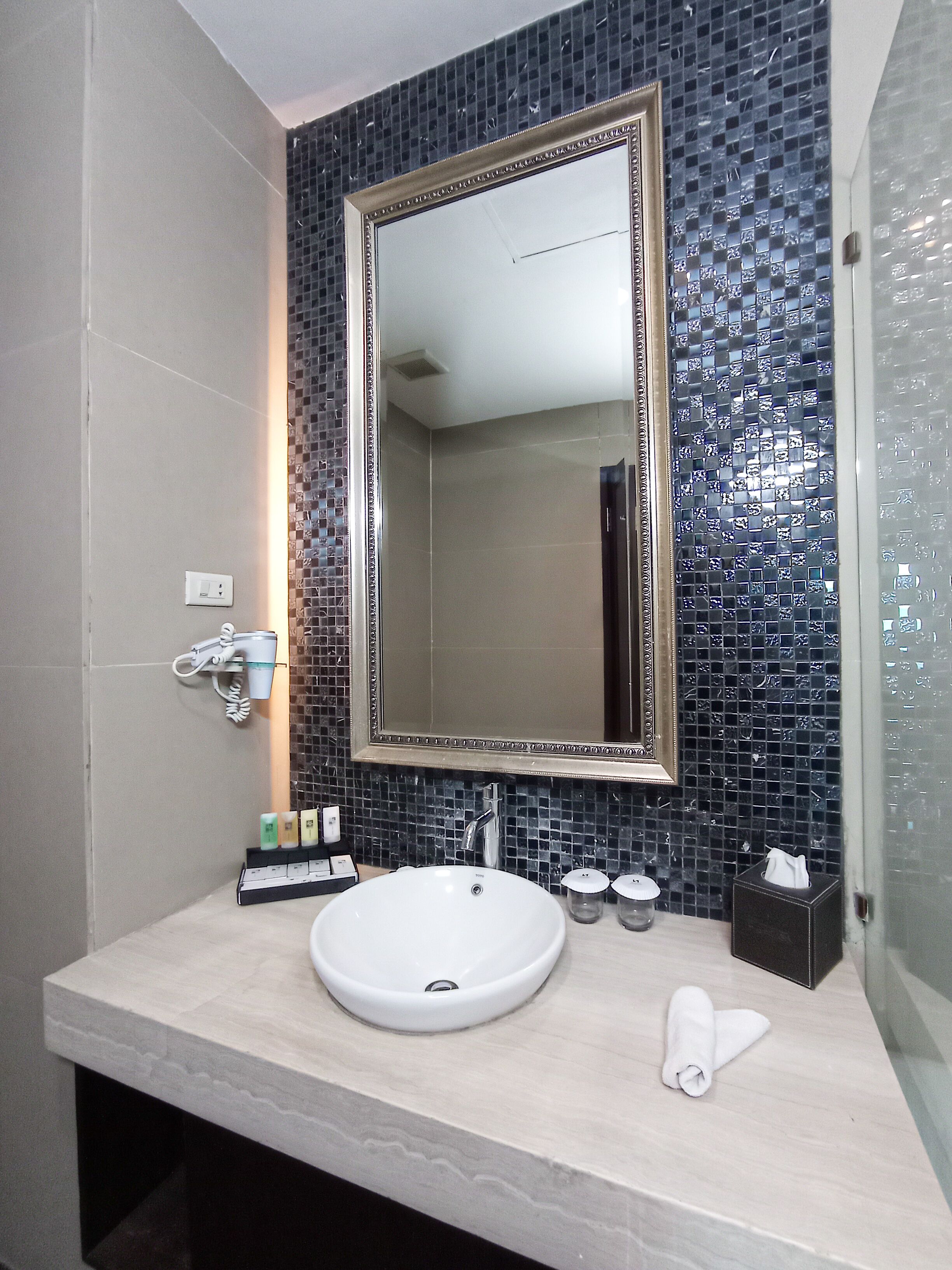 A bathroom with a white sink, a large mirror, and a tiled backsplash.