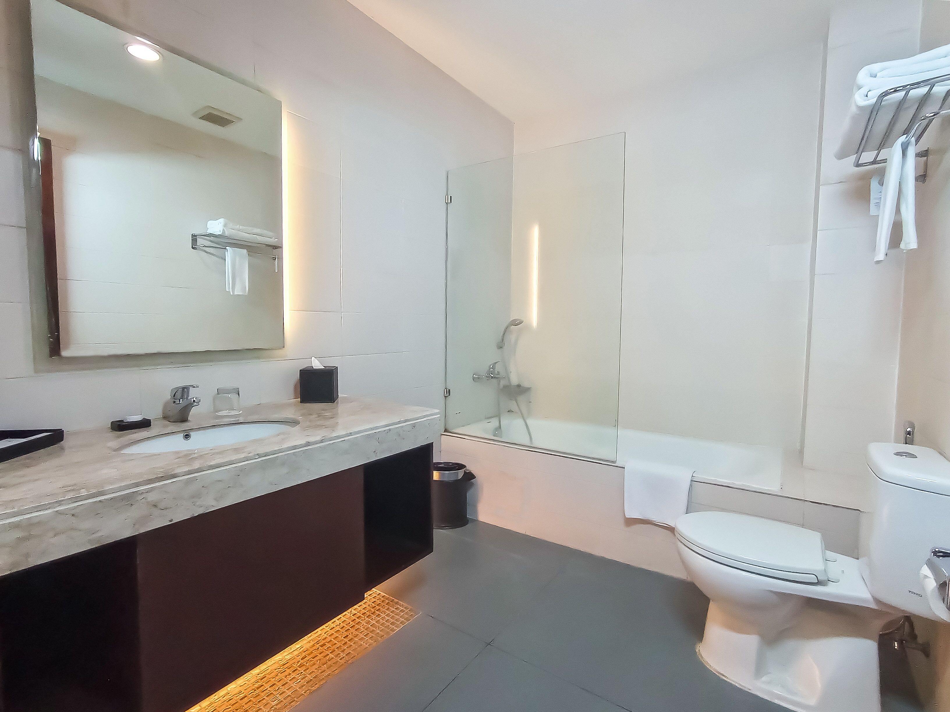 A modern bathroom with a large mirror, a sink, a toilet, and a shower.