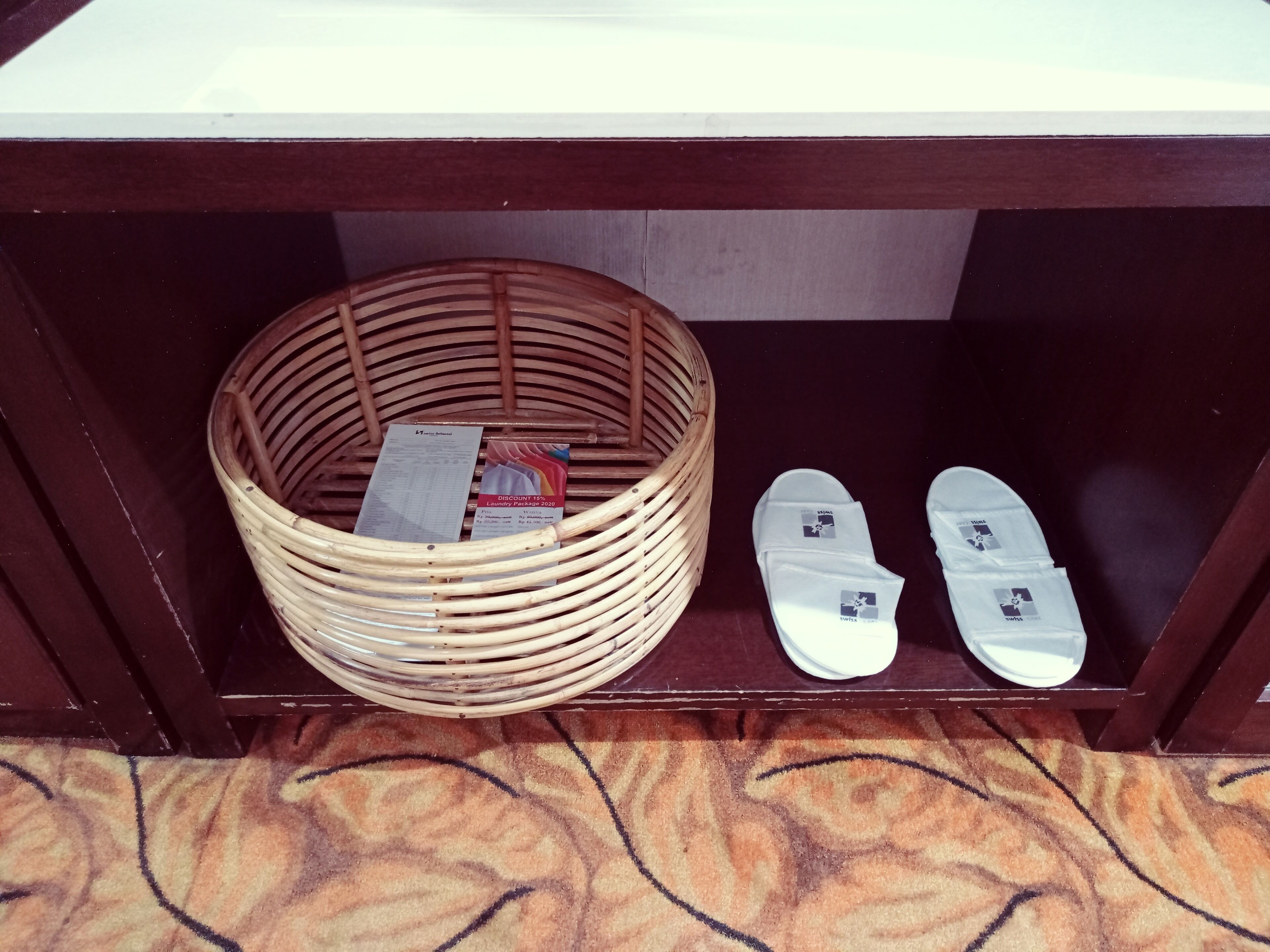 A wicker basket under a wooden table with a patterned rug.