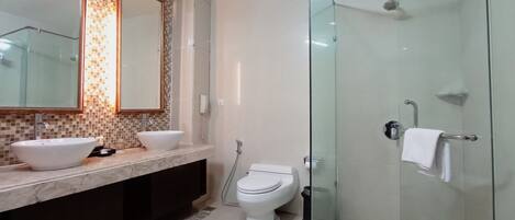 A modern bathroom with a glass shower enclosure, a double sink vanity, and a toilet.