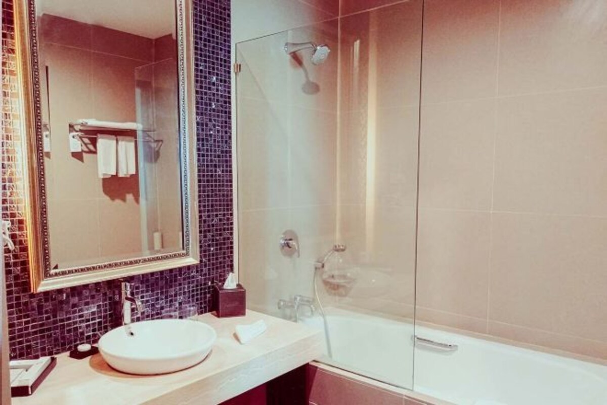 A modern bathroom with a round sink, a large mirror, and a glass-enclosed shower.