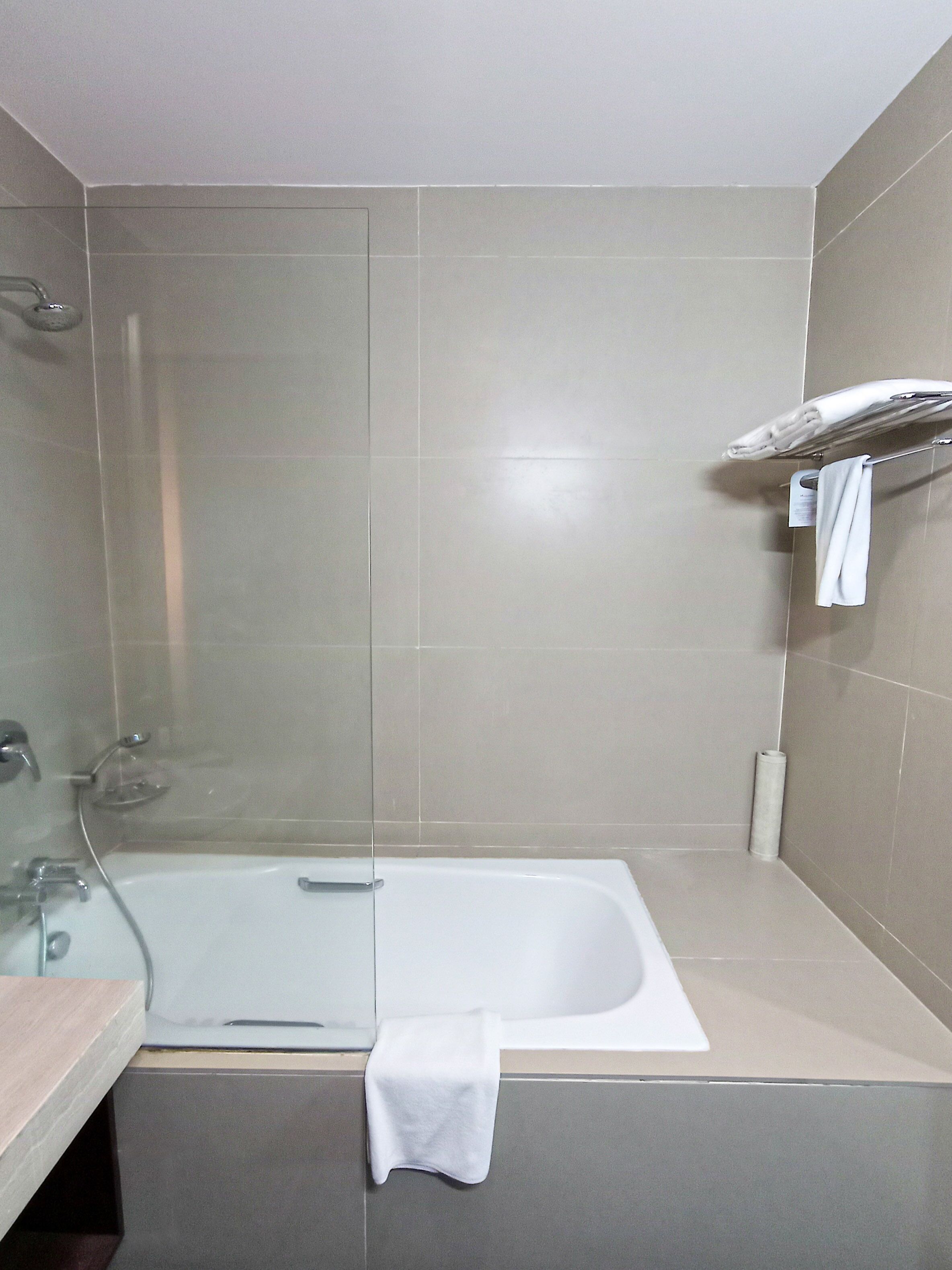 Un baño con bañera, cabina de ducha de vidrio y un perchero para toallas.