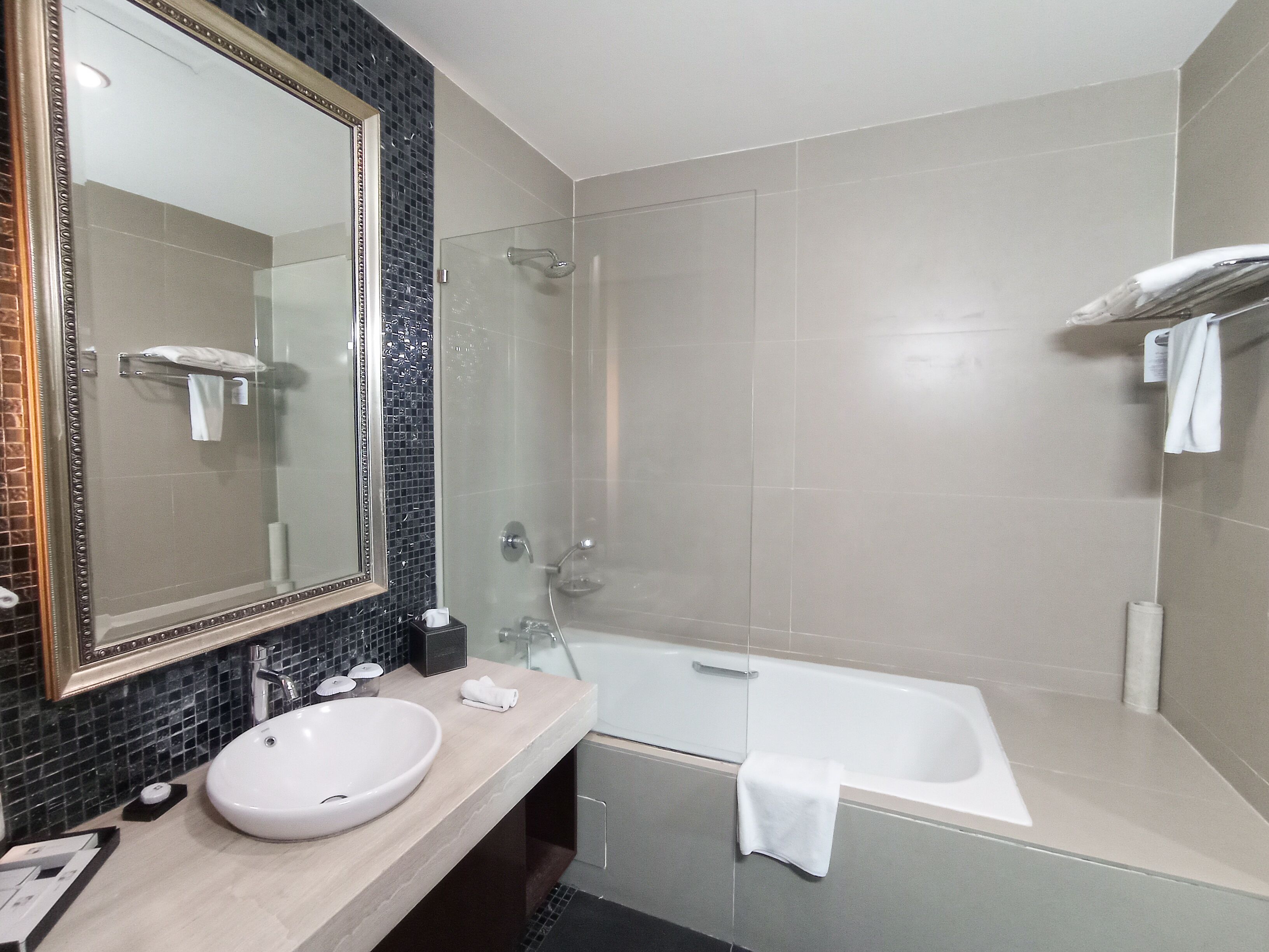 Un baño moderno con un espejo grande, un lavabo redondo, una ducha con paredes de vidrio y una bañera.