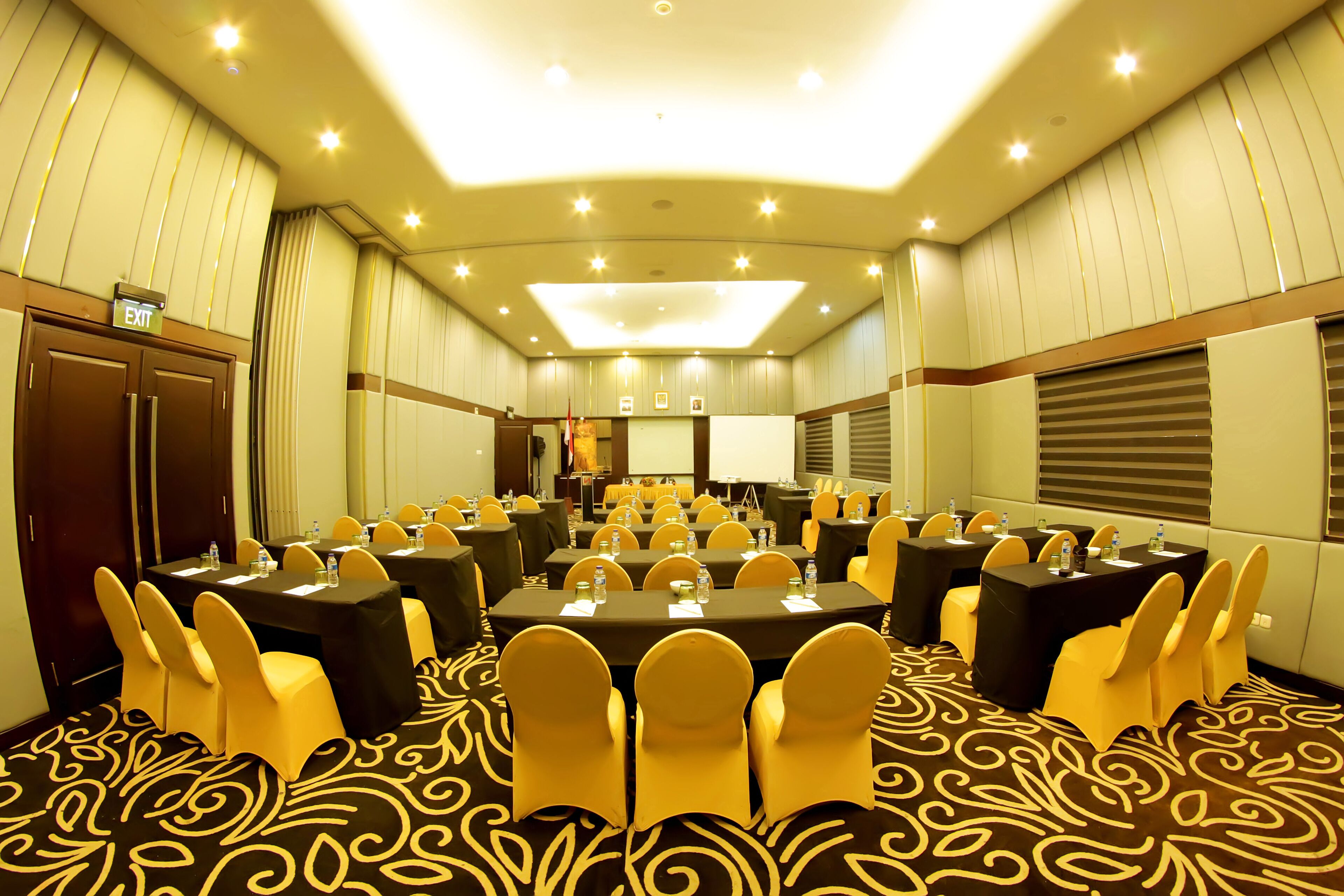 A conference room with multiple tables and chairs, equipped with water bottles and nameplates.