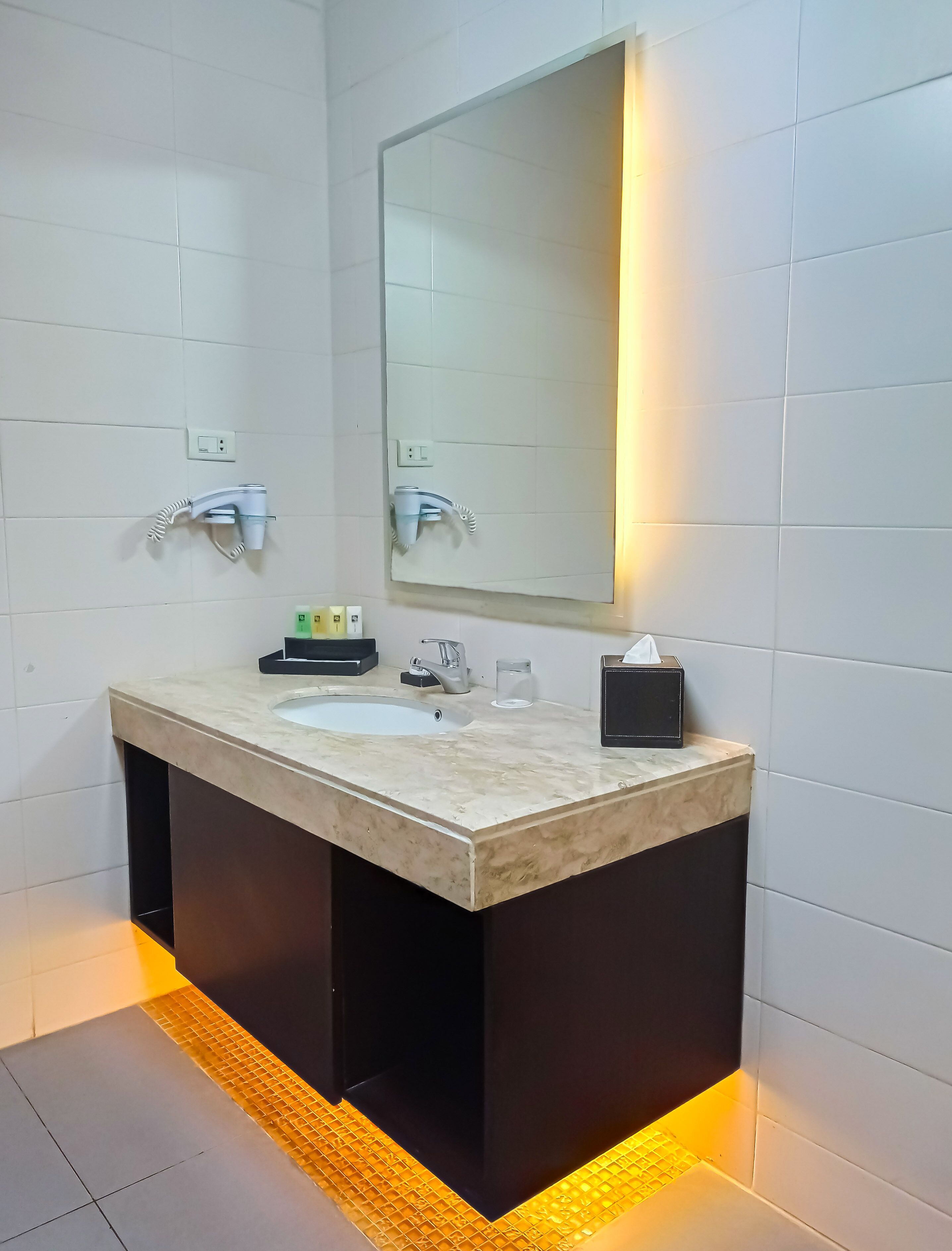 Un baño moderno con un espejo grande, dos lavamanos y suelo con calefacción.