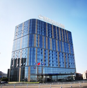 A modern hotel with a curved facade, multiple floors, and a prominent sign at the top. - China National Convention Center (Beijing)