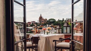 A balcony with a table set for two, overlooking a cityscape with historic buildings. - Rosewood San Miguel De Allende (San Miguel de Allende)