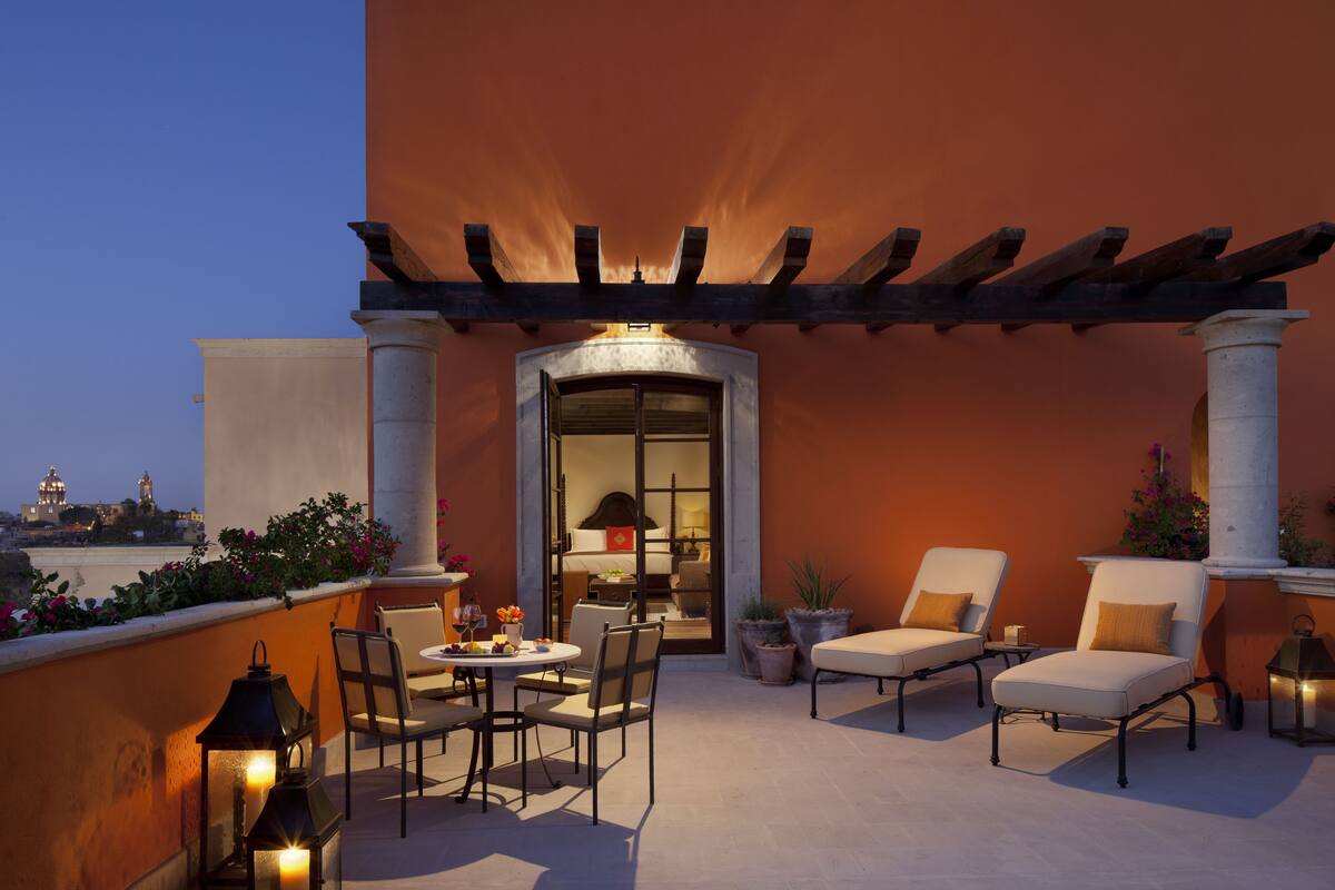 An outdoor patio with a pergola, seating, and a view of a cityscape.