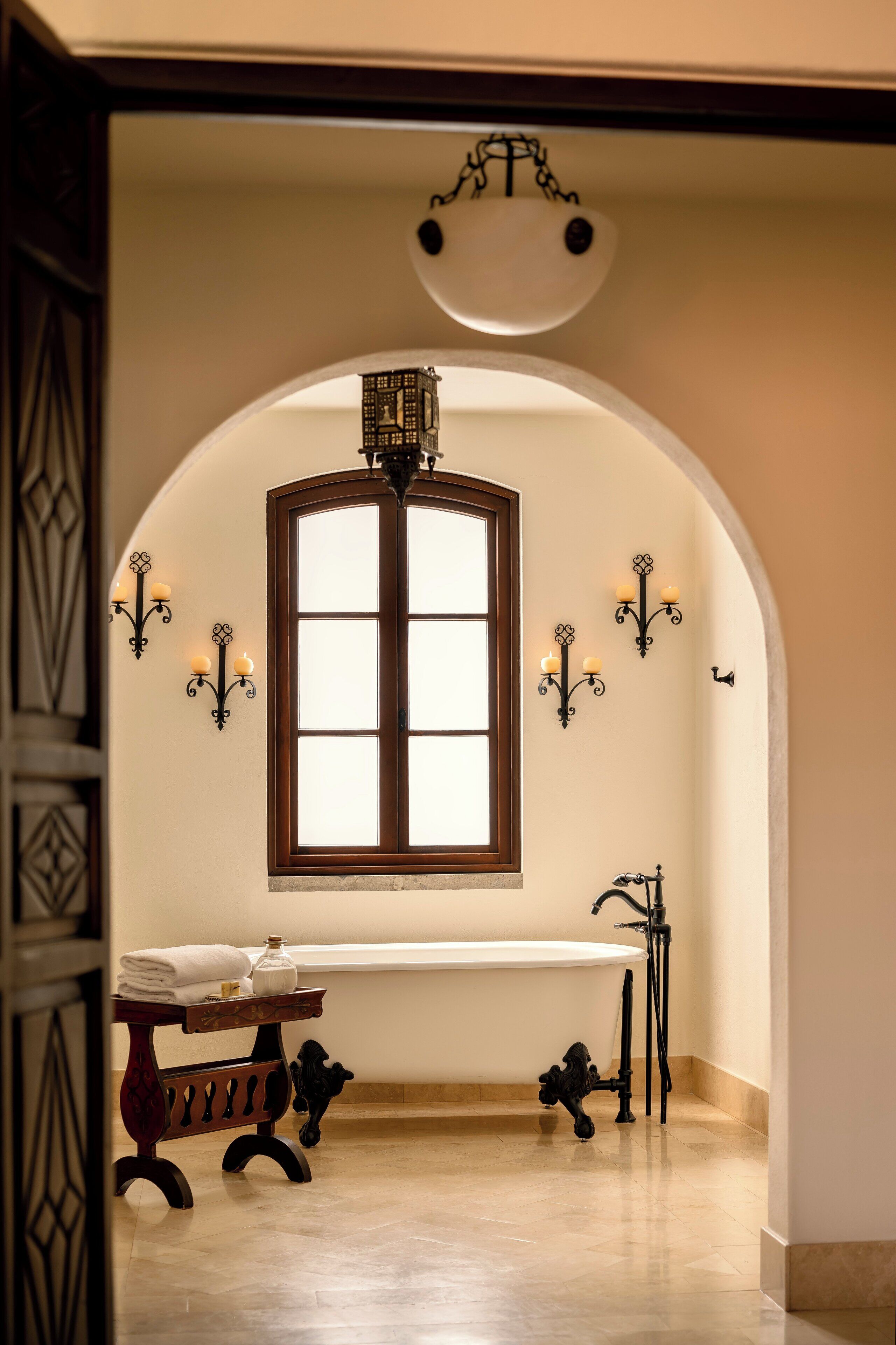 Ein Badezimmer mit einer freistehenden Badewanne, einem Waschtisch mit Spiegel und Wandleuchten.