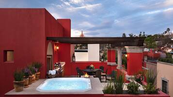 Una terraza en la azotea con jacuzzi, mobiliario exterior y plantas en macetas.