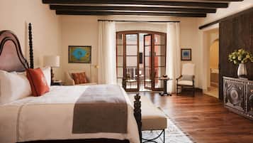 A bedroom with a large bed, a wooden headboard, a bench, and a view of an outdoor patio.