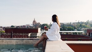 A woman sitting by a pool with a cityscape in the background. - Rosewood San Miguel De Allende (San Miguel de Allende)