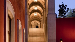 A grand staircase with multiple levels, flanked by columns and illuminated by lanterns, leading to an upper floor. - Rosewood San Miguel De Allende (San Miguel de Allende)