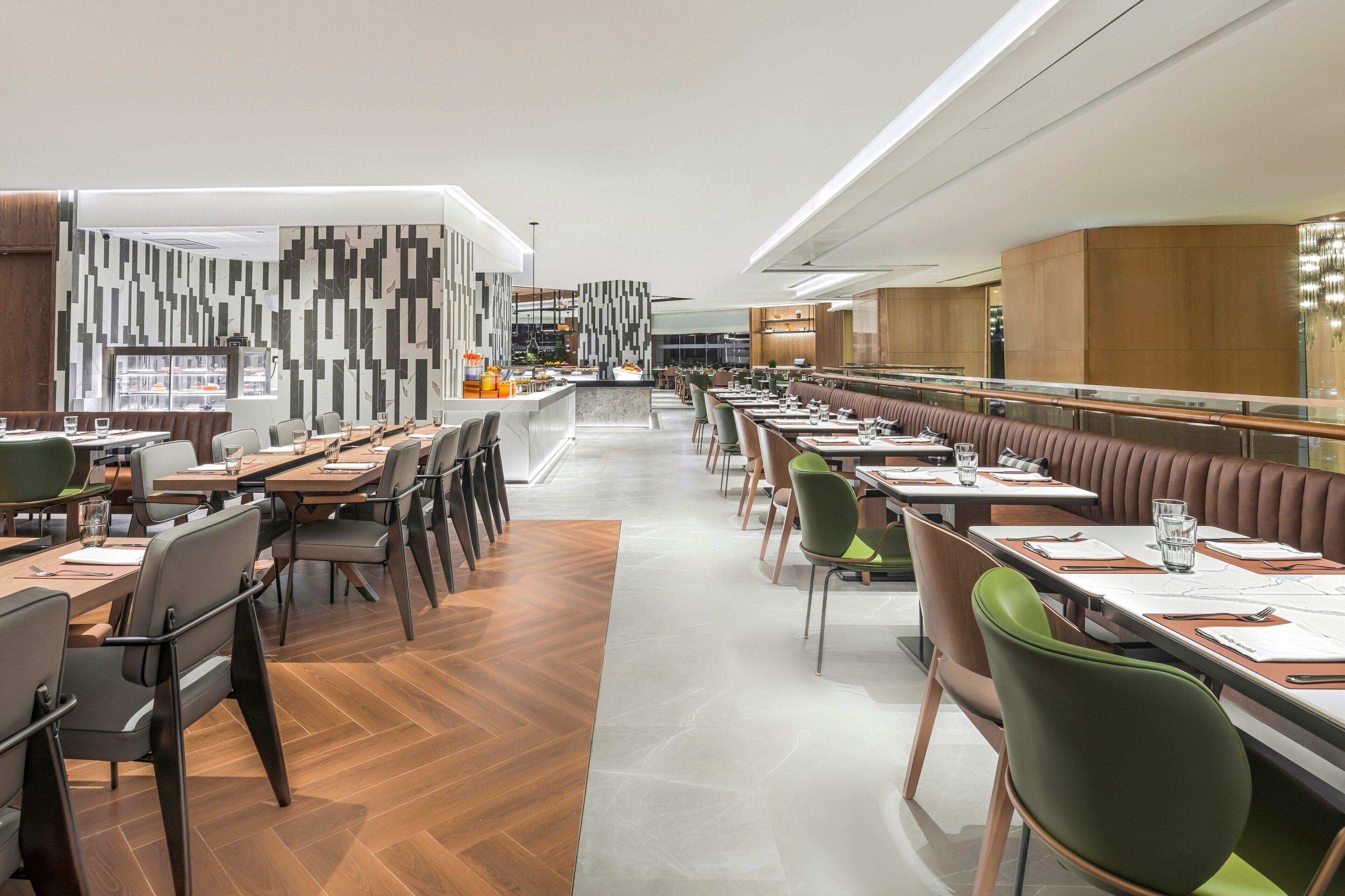 Un restaurante moderno con una barra alargada, cabinas y una pared con diseño.