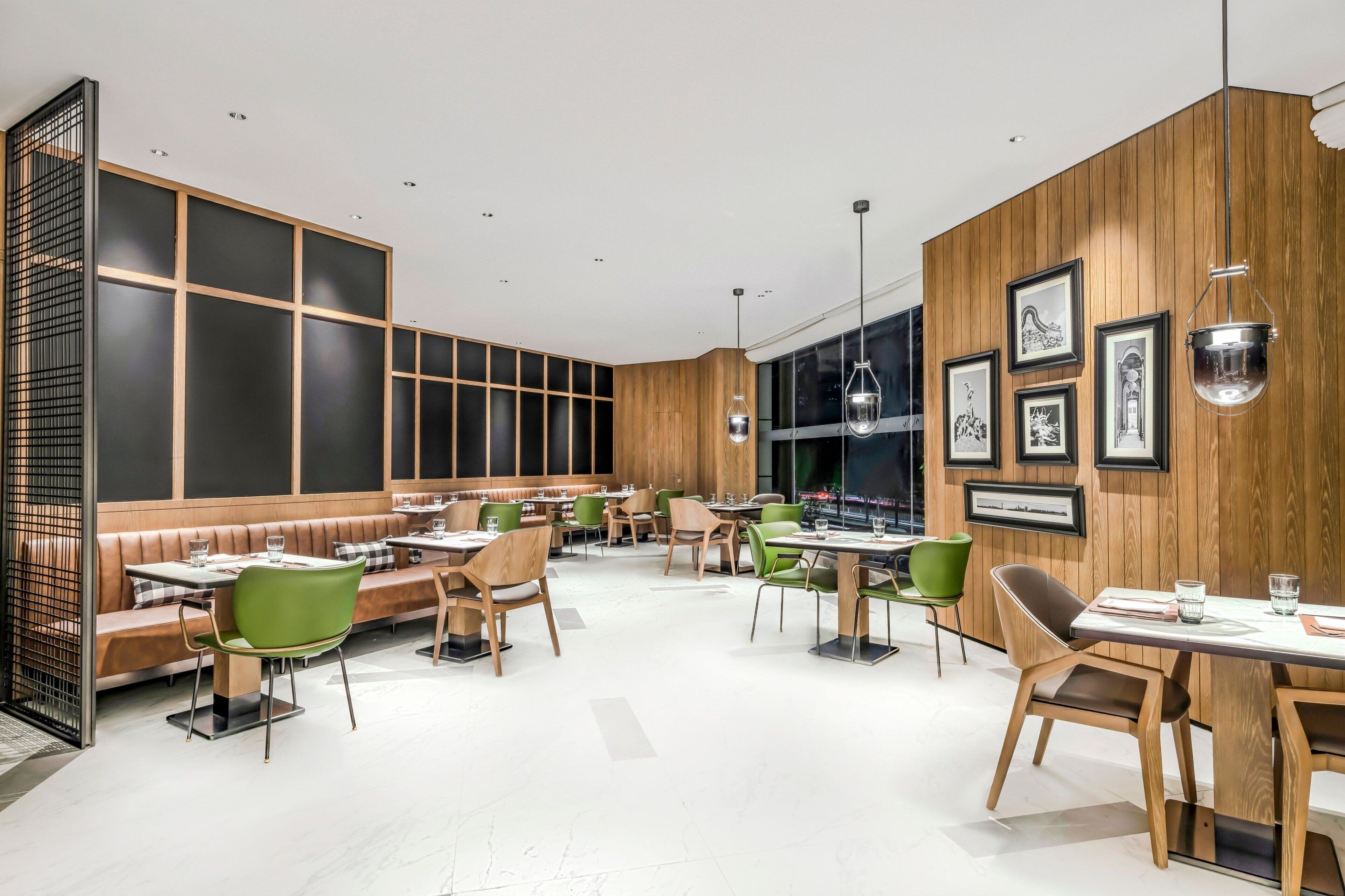 A modern restaurant with wooden paneling, green and brown seating, and pendant lighting.