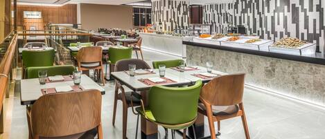 Un restaurante moderno con varias mesas y sillas, una zona de bufé y un diseño de pared contemporáneo.