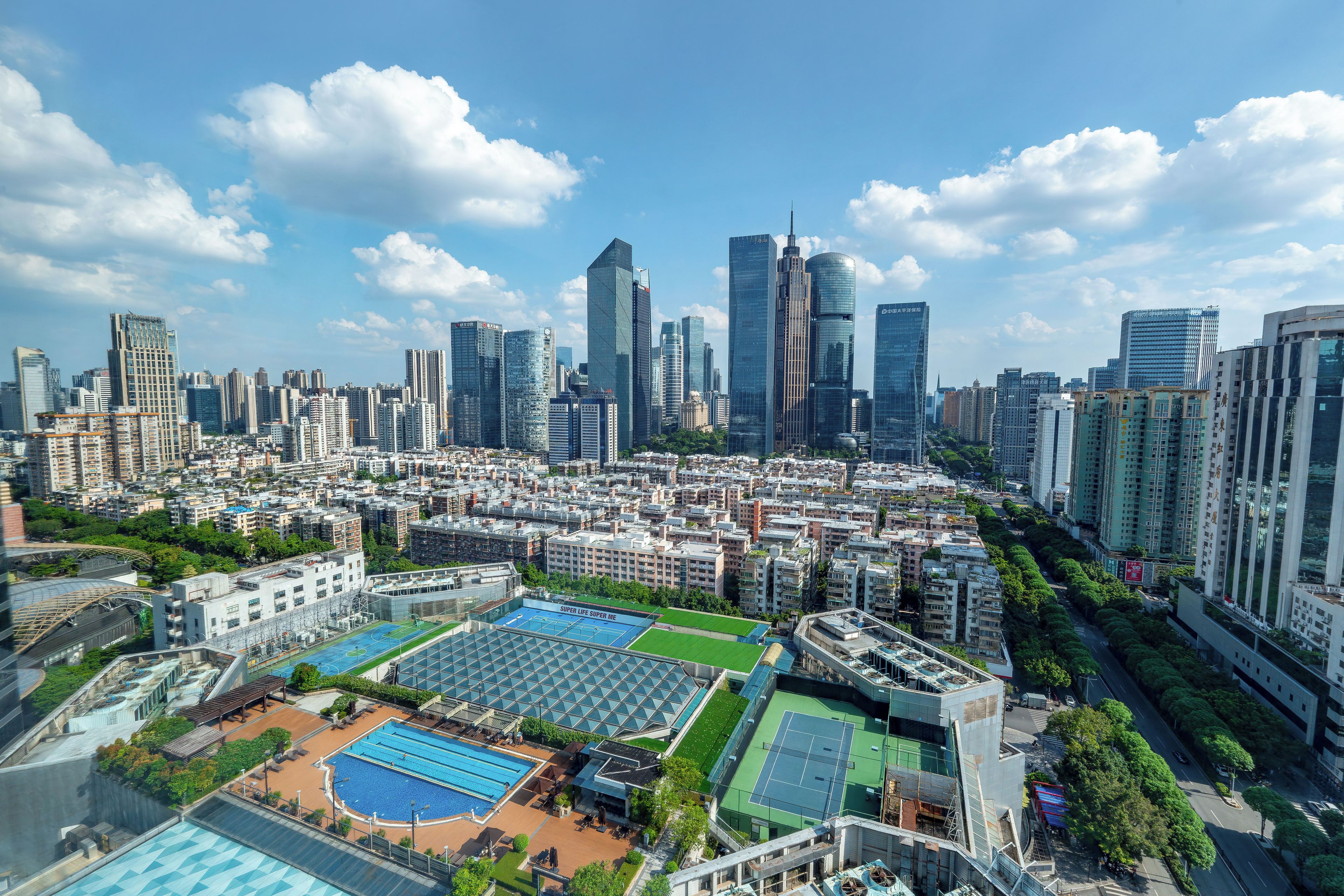 A high-rise residential building with multiple floors, a rooftop pool, and a tennis court.