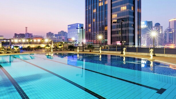 A modern hotel with a large pool area, a prominent building with illuminated windows, and a clear view of the surrounding cityscape. - Sheraton Guangzhou Hotel (Guangzhou)