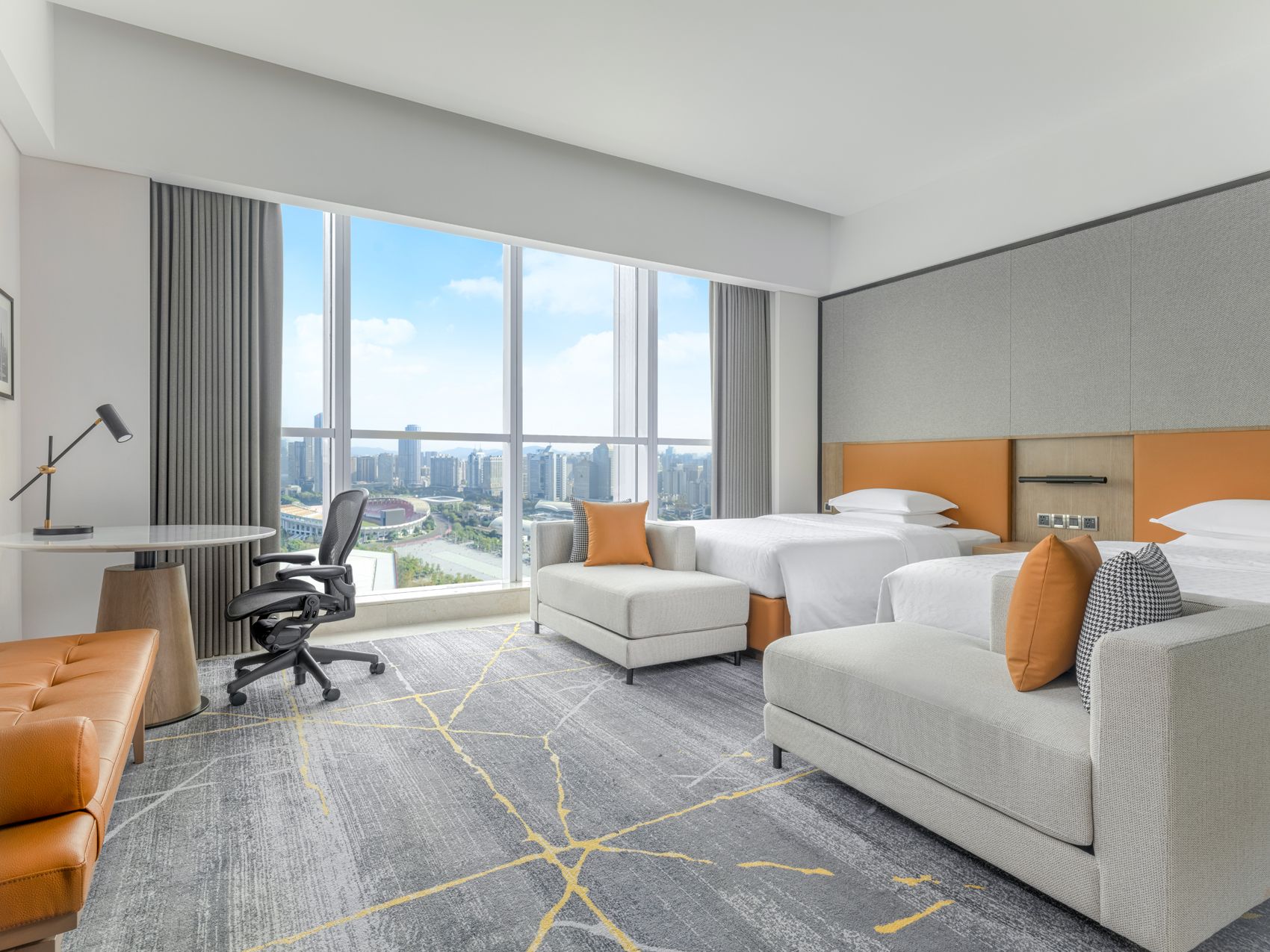 Hotellihuone, jossa on suuri ikkuna, sänky, sohva, työpöytä ja tuoli.