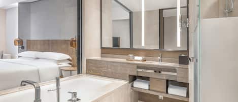 Um banheiro de hotel moderno com um espelho grande, uma banheira, um lavatório com pia e uma área de chuveiro.