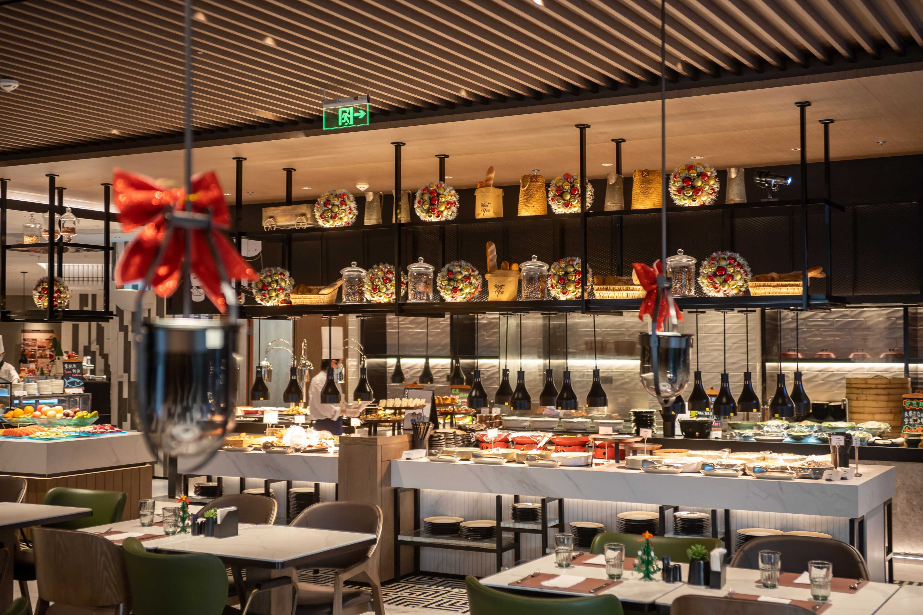 Ein modernes Restaurant mit Buffet, das verschiedene Speisen und dekorative Elemente wie Schleifen und Kränze bietet.