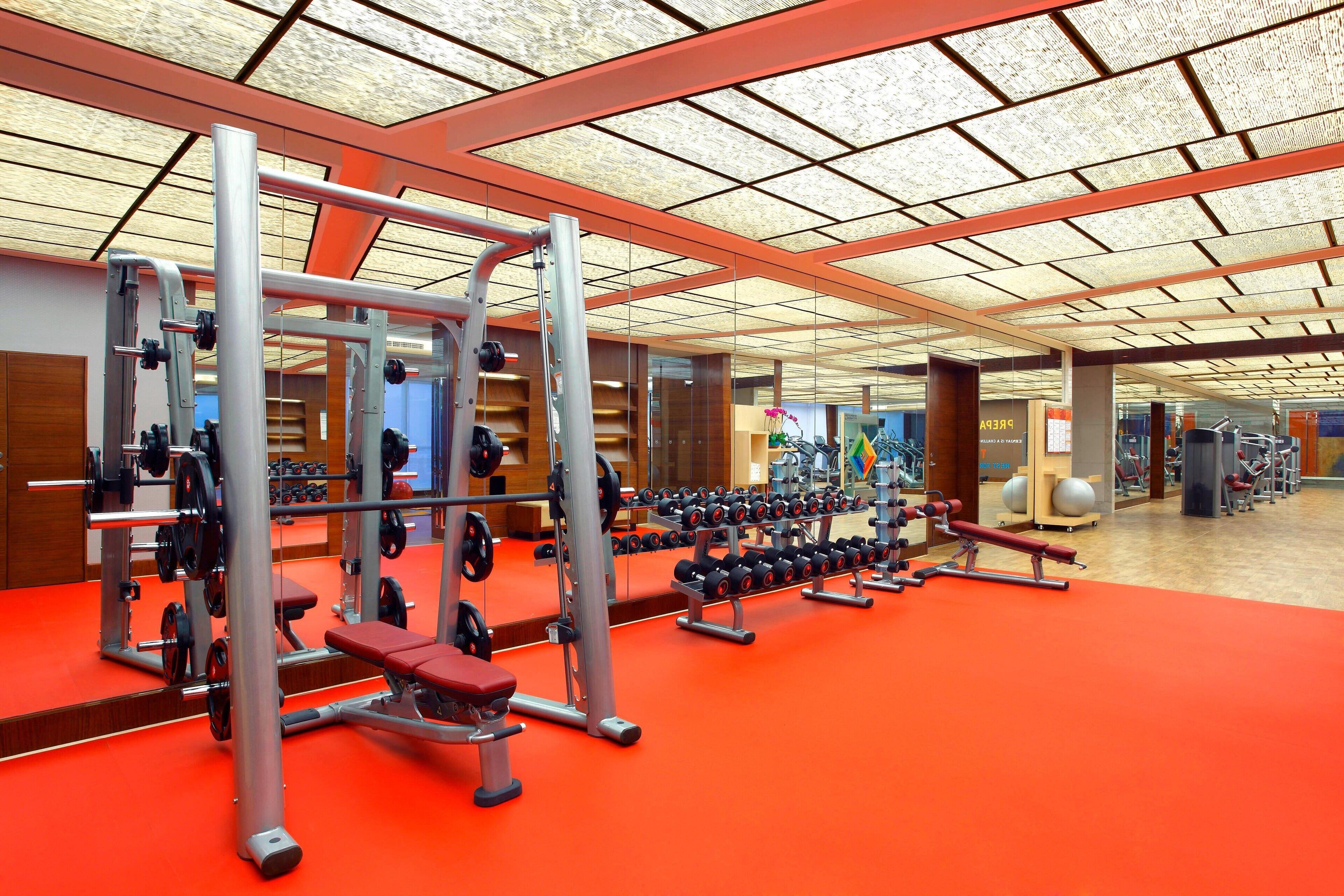 A gym with weightlifting equipment, benches, and dumbbells.