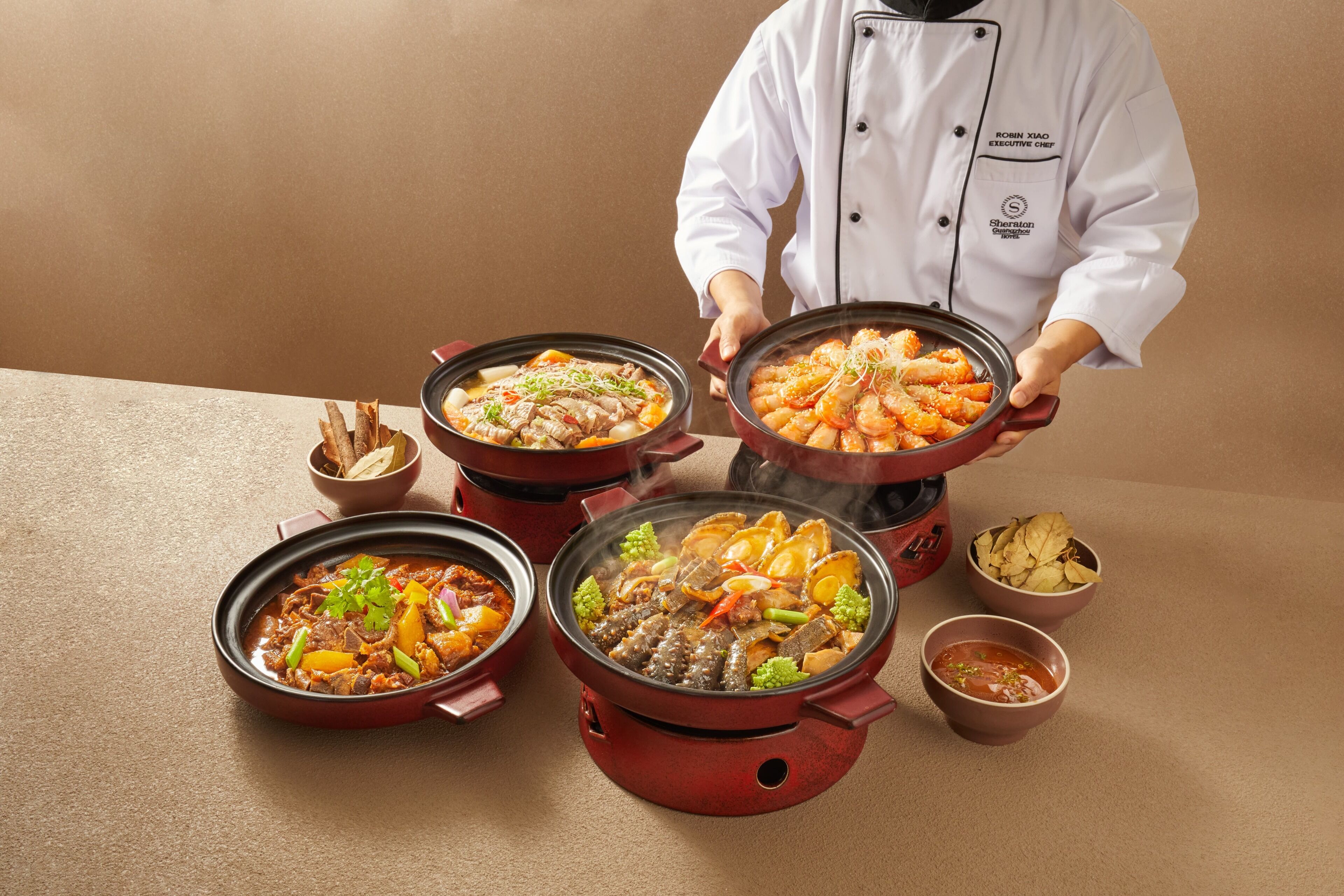 Un chef sostiene una olla de comida, con varios platos de fondo.