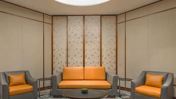 A room with a sofa and two armchairs, a small table, and a patterned floor.