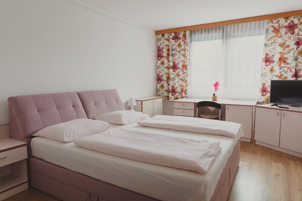 A bedroom with a double bed, a desk, and a chair. - Hotel Karwendel (Innsbruck)