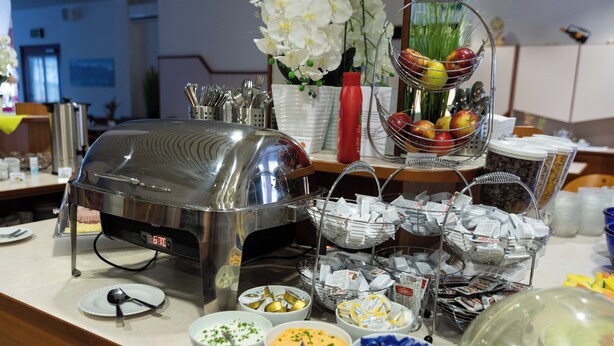 A buffet setup with various food items and utensils. - Hotel Karwendel (Innsbruck)