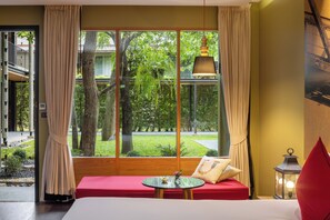 A room with a large window, a red sofa, a small round table, and a hanging lamp. - U Inchantree Kanchanaburi (Kanchanaburi)